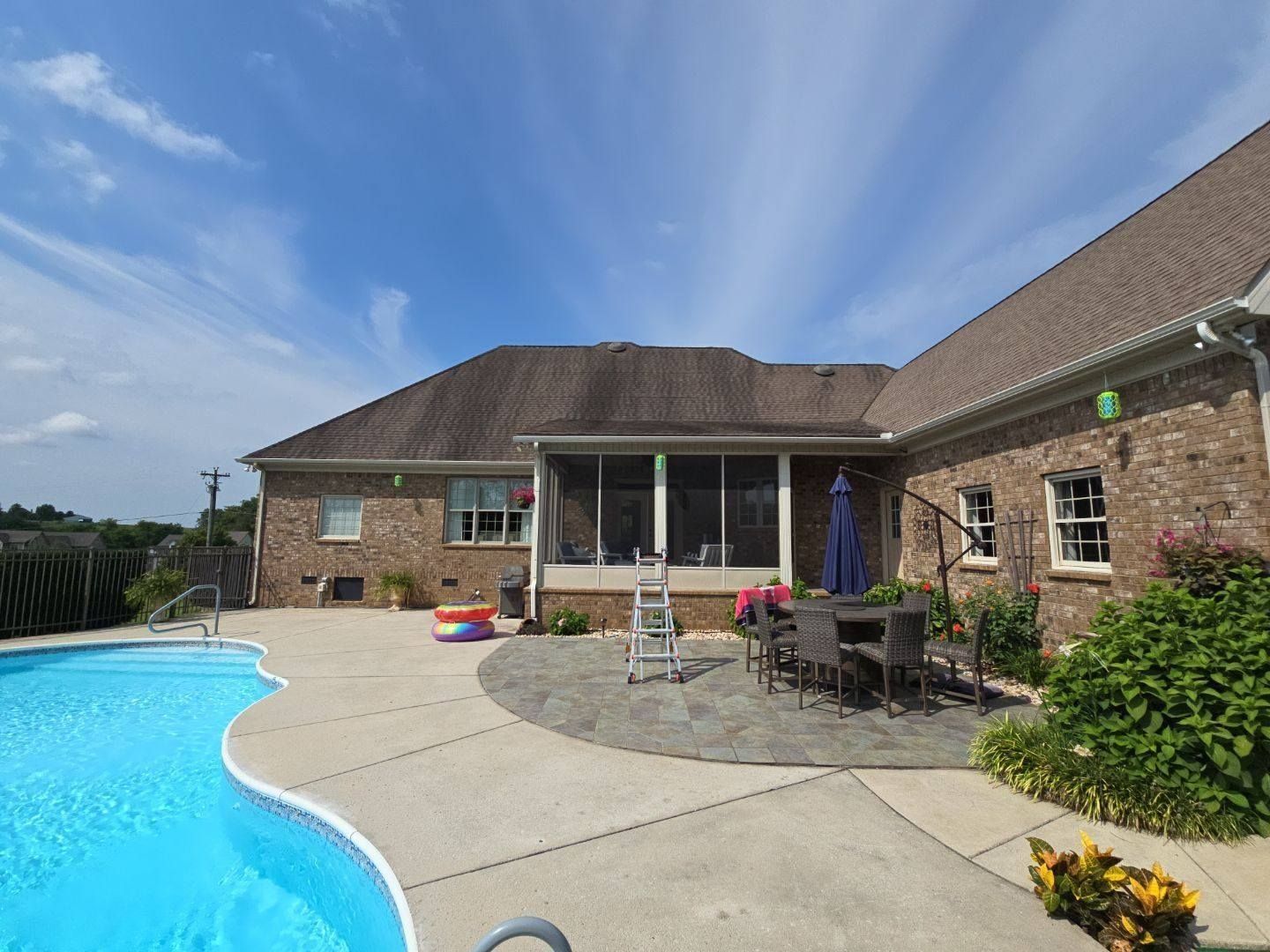 Brick home with a new shingle roof beside a backyard pool
